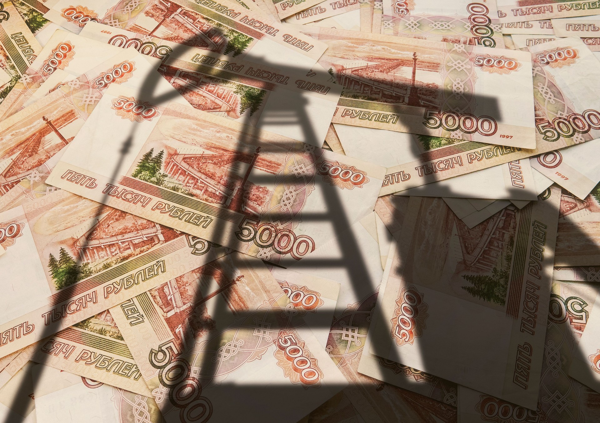 concept of selling minerals for Russian rubles. The shadow of the oil rig against the background of Russian money. Earn money from mining gas and oil energy resources